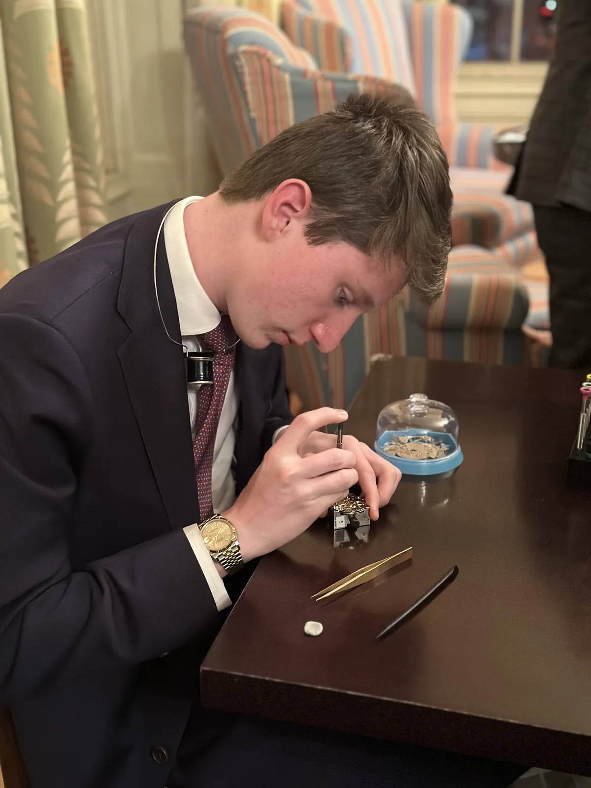 A young watchmaker disassembles a movement at a demonstration table